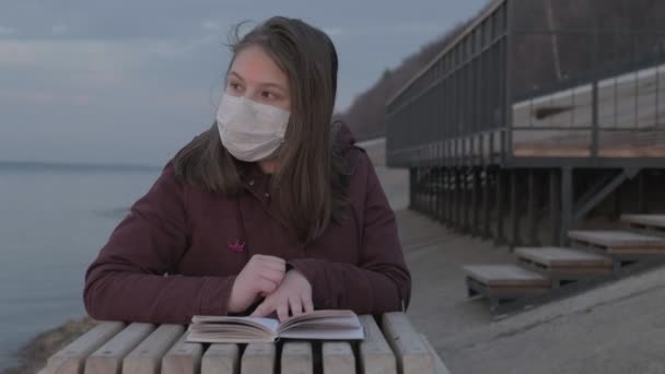 Giovane ragazza in maschera nera da sola all'aperto. Pandemia di coronavirus — Video Stock