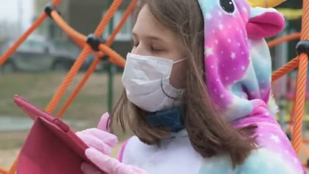 Jong meisje met een beschermend masker op de speelplaats. — Stockvideo