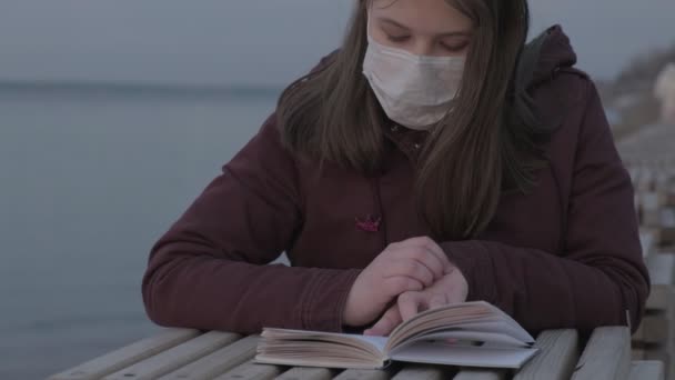 Junges Mädchen in schwarzer Maske allein draußen. Coronavirus-Pandemie — Stockvideo