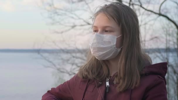Ένα νεαρό κορίτσι με μαύρη μάσκα μόνο στην ύπαιθρο. Πανδημία του Coronavirus — Αρχείο Βίντεο