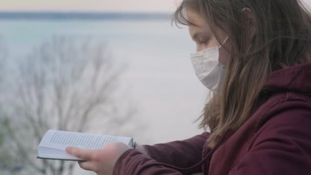 Ένα νεαρό κορίτσι με μαύρη μάσκα μόνο στην ύπαιθρο. Πανδημία του Coronavirus — Αρχείο Βίντεο