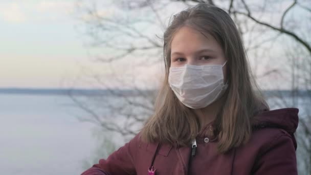 Giovane ragazza in maschera nera da sola all'aperto. Pandemia di coronavirus — Video Stock