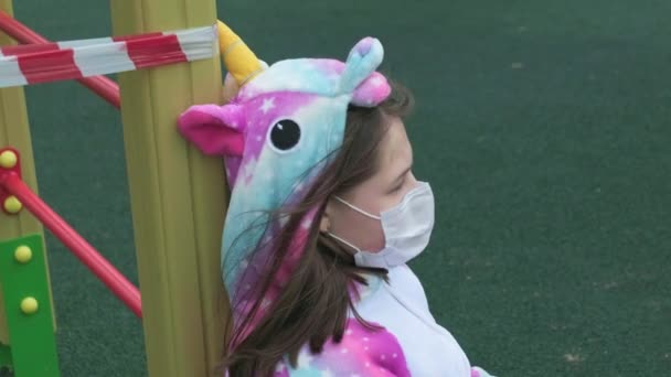 Młoda dziewczyna w masce ochronnej na placu zabaw. — Wideo stockowe