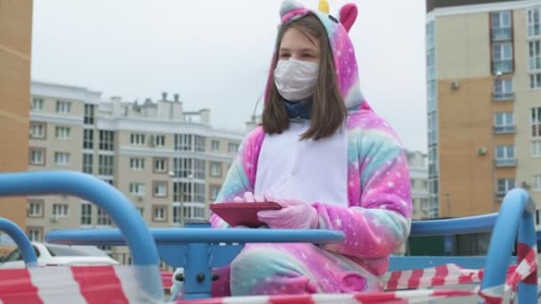 Giovane ragazza con una maschera protettiva al parco giochi . — Video Stock