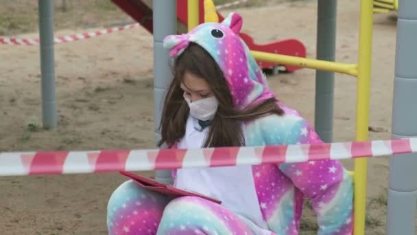 Jong meisje met een beschermend masker op de speelplaats. — Stockvideo