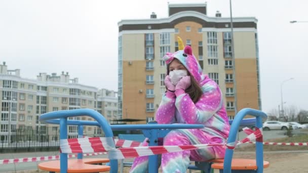 Junges Mädchen mit Schutzmaske auf dem Spielplatz. — Stockvideo