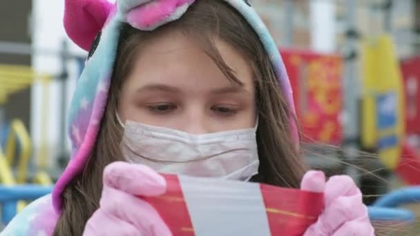 Giovane ragazza con una maschera protettiva al parco giochi . — Video Stock