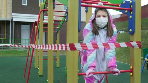 Giovane ragazza con una maschera protettiva al parco giochi . — Video Stock