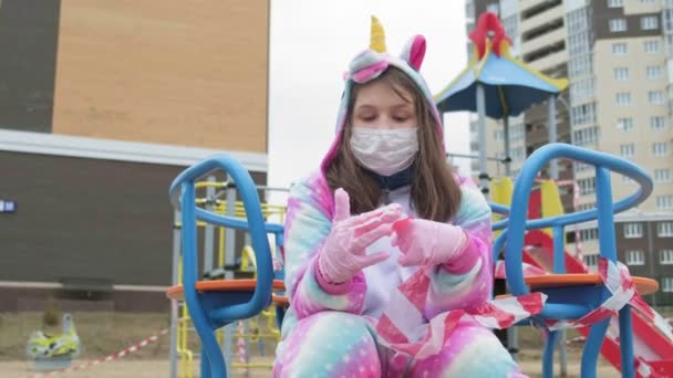 Νεαρό κορίτσι με προστατευτική μάσκα στην παιδική χαρά. — Αρχείο Βίντεο
