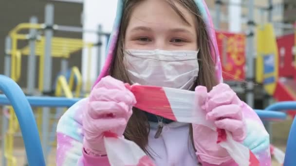 Giovane ragazza con una maschera protettiva al parco giochi . — Video Stock