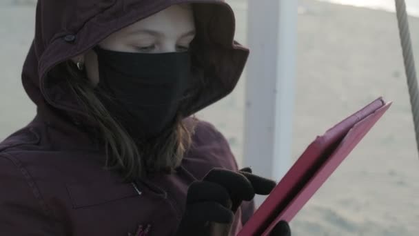 Ragazza in maschera all'aperto utilizza una tavoletta. isolamento — Video Stock