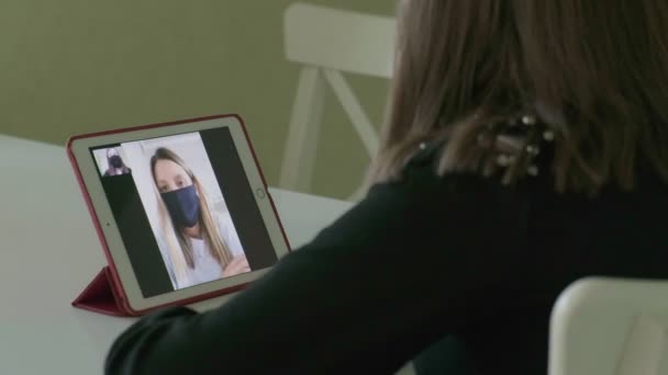 Две молодые женщины разговаривают по видеосвязи в медицинских масках — стоковое видео