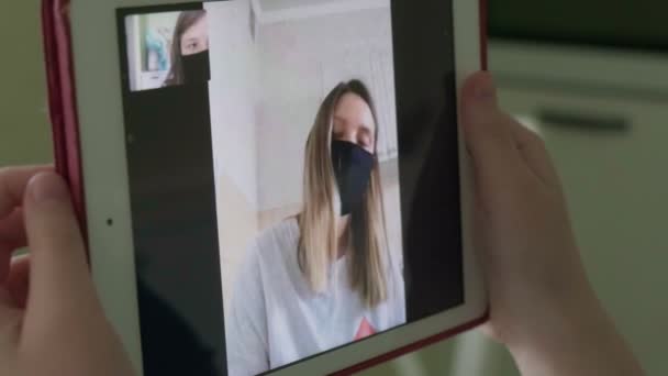 Дві молоді жінки розмовляють через відеозв'язок у медичних масках — стокове відео