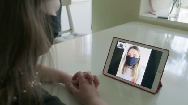Dos mujeres jóvenes están hablando a través de enlace de vídeo en máscaras médicas — Vídeos de Stock
