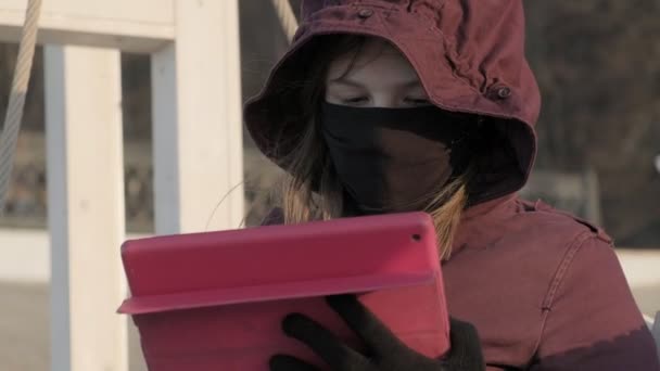 Dışarıdaki maskeli kız tablet kullanıyor. izolasyon — Stok video