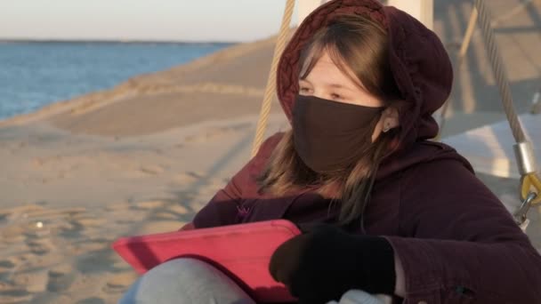 Flicka i mask utomhus använder en tablett. isolering — Stockvideo