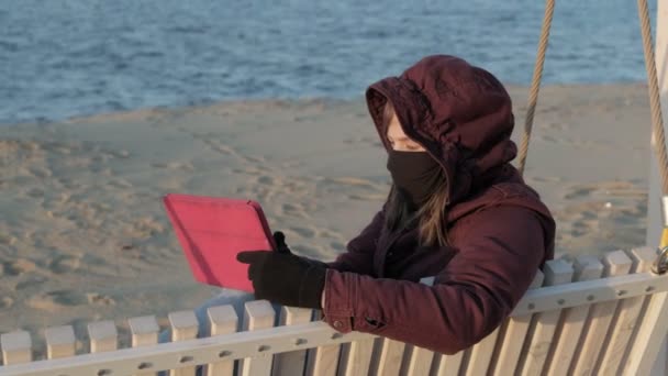 Flicka i mask utomhus använder en tablett. isolering — Stockvideo