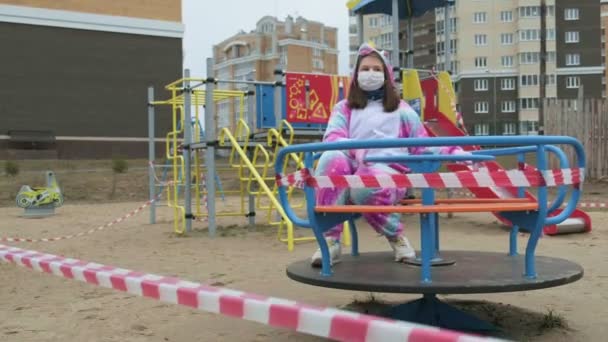 Молода дівчина в захисній масці на дитячому майданчику . — стокове відео