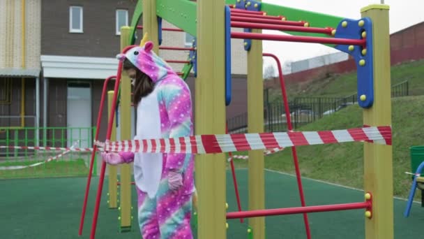 Молодая девушка в защитной маске на детской площадке . — стоковое видео