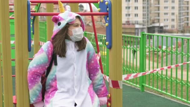 Chica joven con una máscara protectora en el patio de recreo . — Vídeo de stock