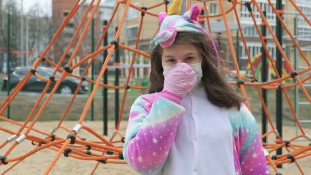 Młoda dziewczyna w masce ochronnej na placu zabaw. — Wideo stockowe