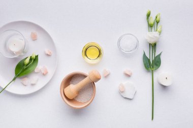 Yağlı spa kompozisyonu, deniz tuzu, mumlar ve beyaz arka planda beyaz bir Eustoma dalı. en üstteki görünüm