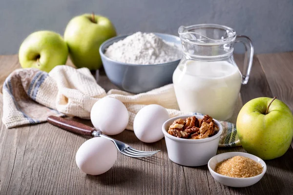 Milk, flour, eggs and green apples on a wooden table. Ingredients for apple charlotte. Recipe