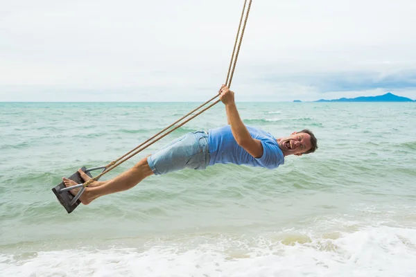 Funny man on the beach swing — Stock Photo, Image