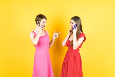 iki genç kadın akıllı telefonlar ile konuşurken gülümseyen