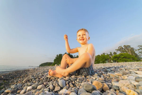 Boy sitting on the beach and playing — Stock Photo, Image
