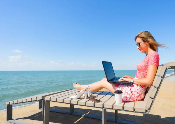 Kvinna sitter på stranden stolen med laptop — Stockfoto