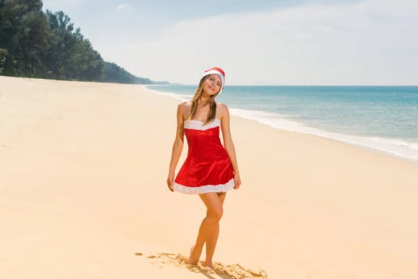 Mulher em roupas de Natal vermelho na praia do mar — Fotografia de Stock