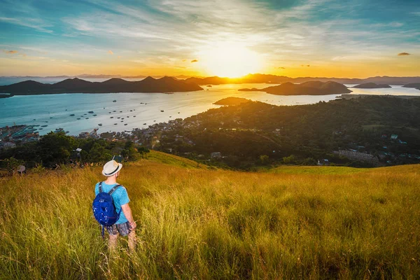 ハイカーのバックパックを丘の上に立っていると 夕日と島を探して帽子 旅行や休暇の概念 — ストック写真