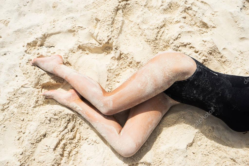 Womans body on the beach in sand. 