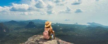 Young woman with backpack enjoying breathtaking view of the landscape from the top of mountain. Travel comcept. Back view. Banner edition. clipart