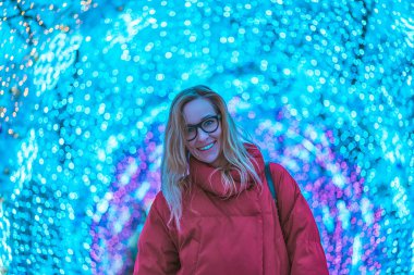 Arka plan üzerinde birçok mevsimlik ışıklı gözlük genç gülümseyen kadın. Tonda renkli.