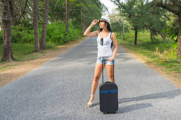 年轻妇女旅行者在帽子和与手提箱在乡间路 — 图库照片