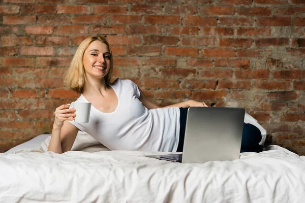 Jovem Mulher Feliz Com Xícara Café Laptop Deitado Cama Parede — Fotografia de Stock