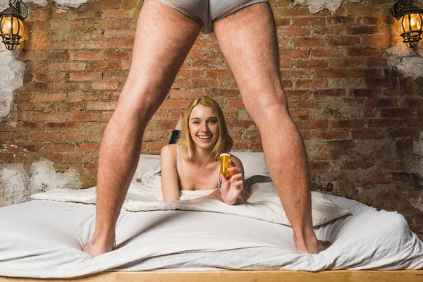 ベッドで横になっている若い女性 男性の性器を見ていると薬を示す薬です セクシュアリティとインポテンツの問題概念 — ストック写真