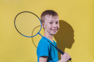 Sarı arka plan üzerinde izole badminton raket ile mutlu çocuk.