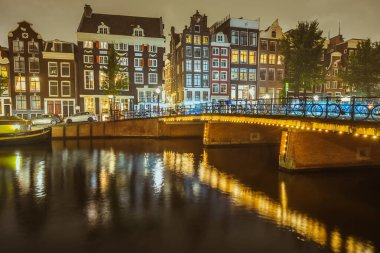 Amsterdam Kanalı Panorama 'sı tipik Hollandalı evleri ve geceleri Hollanda, Hollanda' da köprüsü olan Singel. Hareket halindeki su bulanık.
