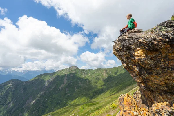Çocuk kayanın tepesinde oturuyor. Svaneti, Georgia. Seçici odak.