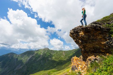 Kayanın tepesindeki kadın turist. Svaneti, Georgia. Seçici odak.