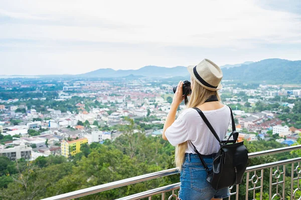 年轻漂亮的女人头戴礼帽 带着相机站在高亮的视点上 泰国普吉 — 图库照片