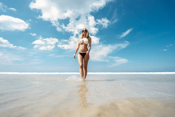 若い美しい女性が砂浜で水の上を歩く — ストック写真
