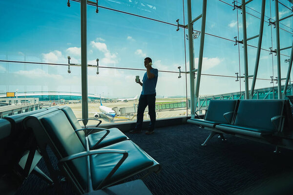 Силуэт пассажира с кофе в руке разговаривает по мобильному телефону в аэропорту. Концепция путешествия
.