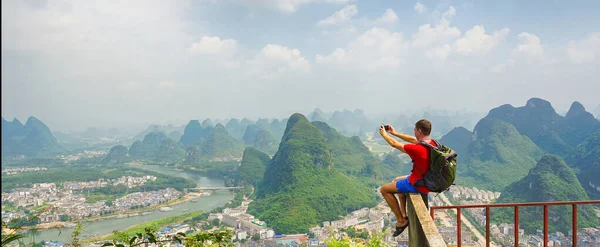 Turista Batohem Vyfotit Svém Smartphonu Vrcholu Kopce Výhledem Město Yangshuo — Stock fotografie