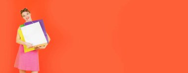 Kırmızı arka planda alışveriş torbaları olan mutlu bir kadın. Stüdyoda renkli bir portre. Pankart sürümü