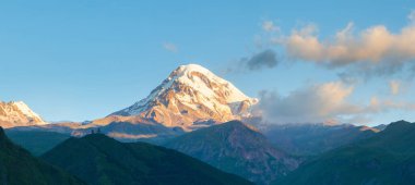 Beautiful sunrise in Stepancminda, Georgia. View to the Kazbek mountain and Trinity church. Banner edition.	