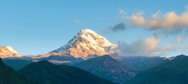 Beautiful sunrise in Stepancminda, Georgia. View to the Kazbek mountain and Trinity church. Banner edition.